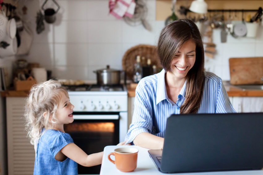 Working mom works from home office. Happy mother and daughter smiling. Successful woman