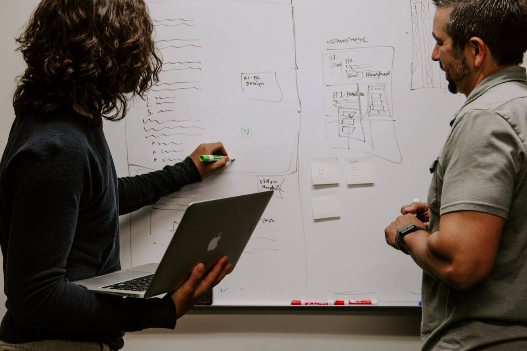 man and woman writing on white board