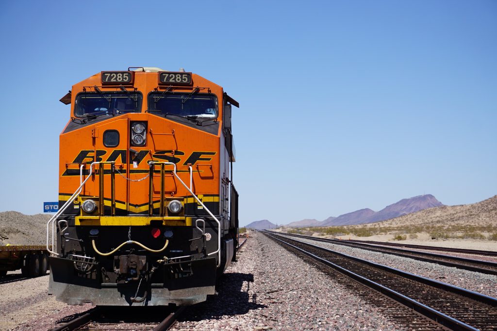 an orange train traveling down train tracks next to mountains