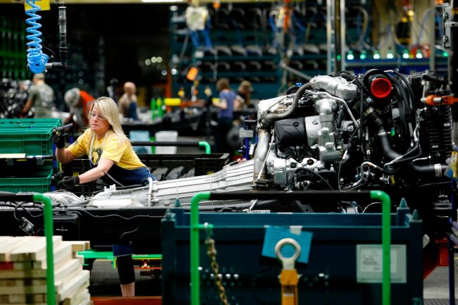 merlin_160827738_341f1f8e-5768-4cb0-938a-38bfdac4282d-superJumbo a woman working on a car in a factory