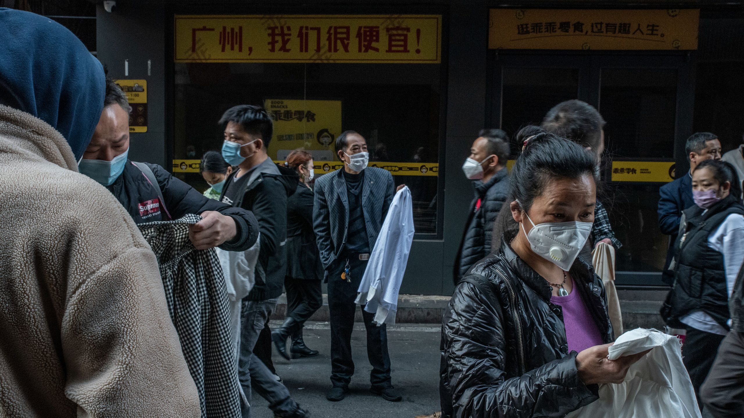 a group of people walking down a street wearing face masks