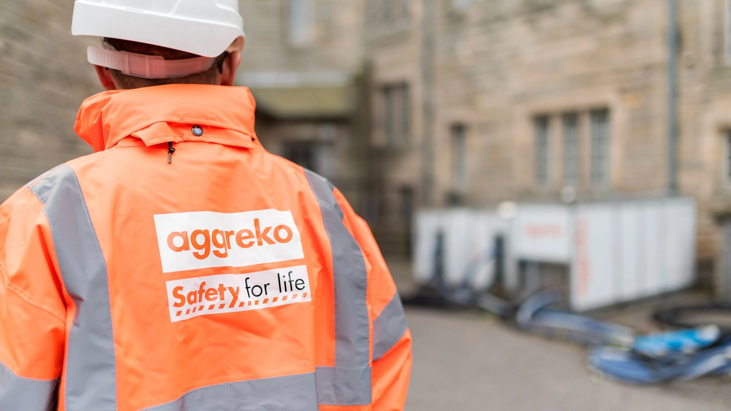 Aggreko technician wearing safety gear and standing in a UK street